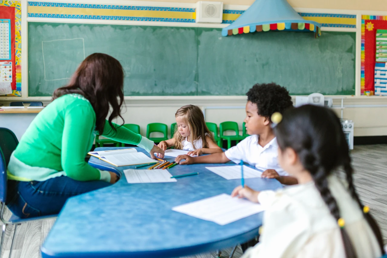 Crianças e educadora participam de uma atividade de aprendizagem. Fotografia ilustrativa.